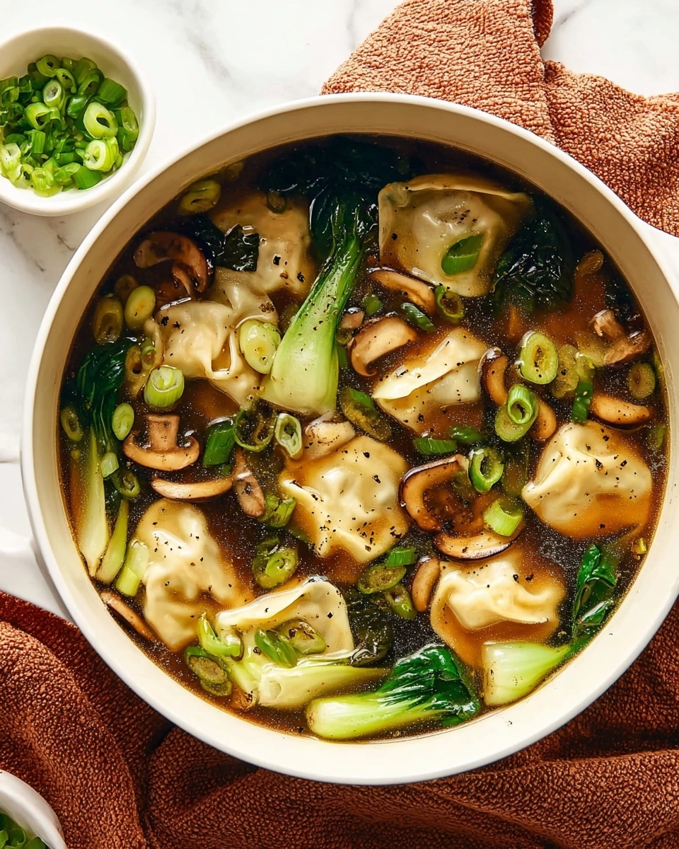 A white pot filled with dark brown clear broth holding several light beige dumplings spread evenly across the surface. Bright green pieces of bok choy float among the dumplings, adding a fresh, leafy texture. Thinly sliced, brown shiitake mushrooms are scattered throughout, blending in with small rounds of vibrant green chopped scallions that add pops of color on top. A few specks of black pepper are sprinkled on the ingredients, visible on the dumplings and greens. The pot sits on a soft, textured, rust-colored cloth over a white marbled surface, with a small white bowl of extra chopped scallions nearby. Photo taken with an iphone --ar 4:5 --v 7